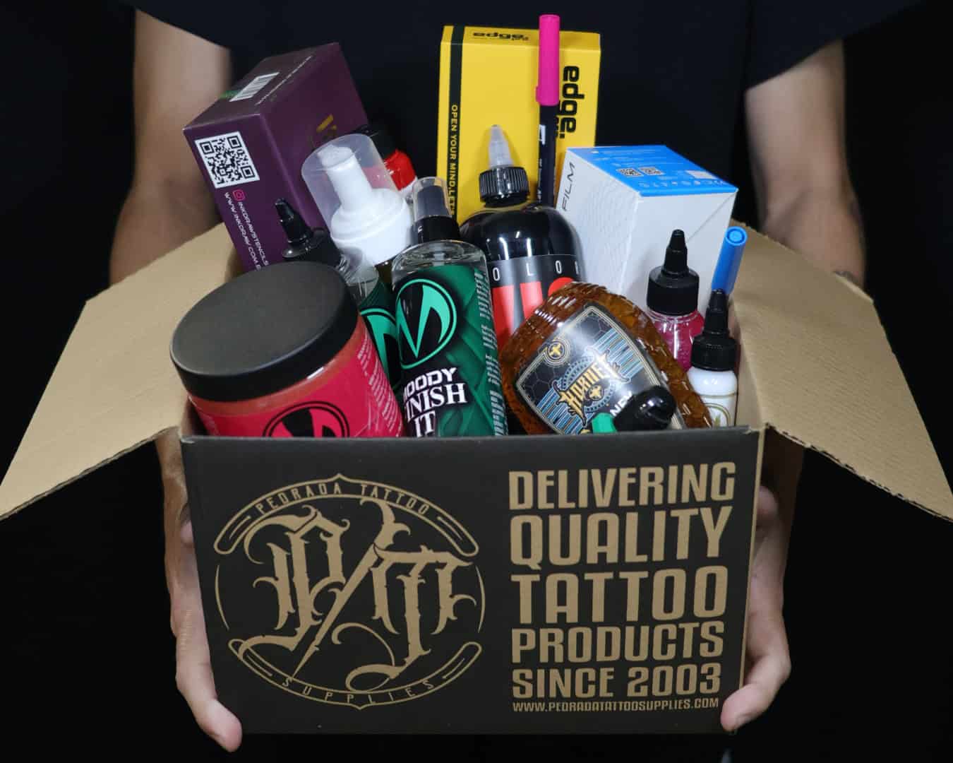 Assorted tattoo supplies including inks, needles, and equipment in a box.